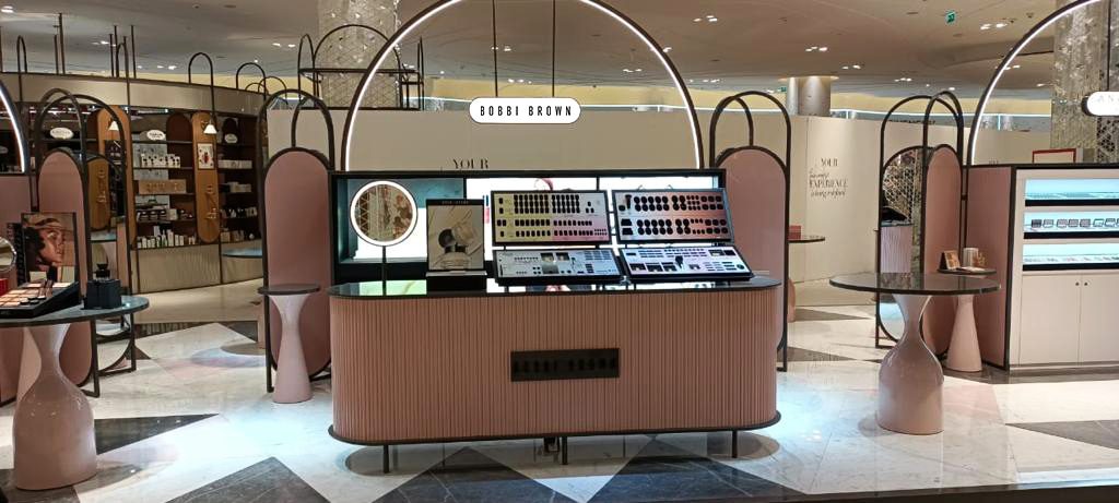 Custom beauty counter with arched branding and digital screens